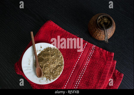 Photographie artistique de la yerba mate infusion, typique de l'Argentine, dans une assiette blanche, sur un fond de bois foncé Banque D'Images