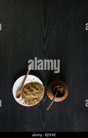 Photographie artistique de la yerba mate infusion, typique de l'Argentine, dans une assiette blanche, sur un fond de bois foncé Banque D'Images