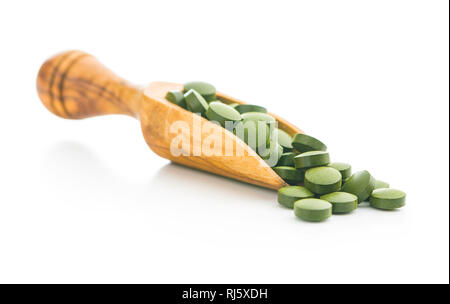La chlorelle vert comprimés ou l'orge en pillsin scoop en bois isolé sur fond blanc. Banque D'Images