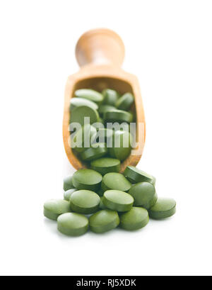 La chlorelle vert comprimés ou l'orge en pillsin scoop en bois isolé sur fond blanc. Banque D'Images