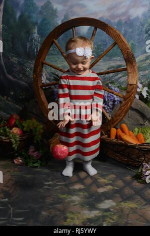 Little Blue Eyed Girl in Red stripe robe. Jouer et poser. Banque D'Images