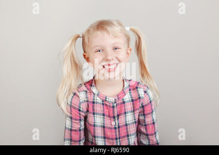 Closeup portrait of cute adorable blond Caucasian preschool girl smiling in front of camera en studio. Rire des enfants posant sur du bac de lumière Banque D'Images