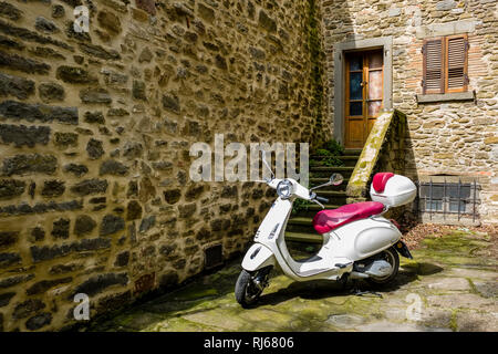 Un scooter Vespa blanc garé entre vieilles maisons de la ville médiévale Banque D'Images