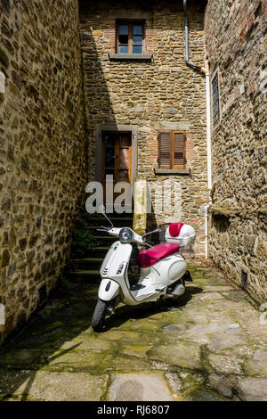 Un scooter Vespa blanc garé entre vieilles maisons de la ville médiévale Banque D'Images