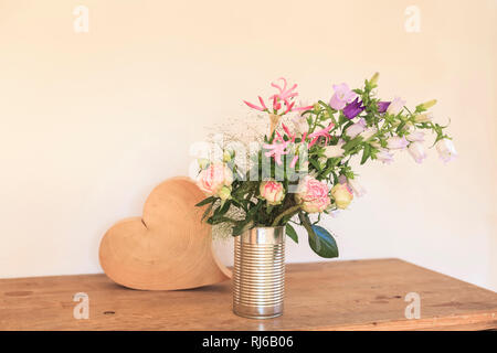 Strauß Sommerblumen, Dose, Vase als ein Herz aus Holz daneben Banque D'Images