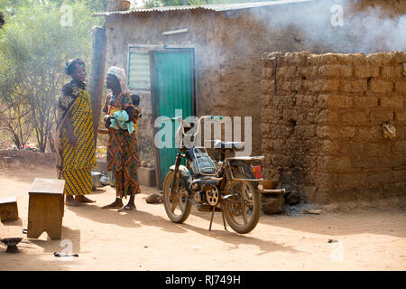 Village de Karfiguela, Banfora, région de Cascades, Burkina Faso, 6 décembre 2016; Sanata Kone, benifmagistrature, (tenue rouge et grise), parlant avec des amis sur le chemin de son champ. Banque D'Images