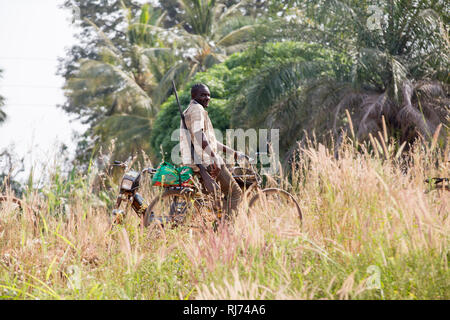 Village de Karfiguela, Banfora, région de Cascades, Burkina Faso, 6 décembre 2016; chasseur sur son vélo sur le chemin de la recherche de viande de brousse. Banque D'Images