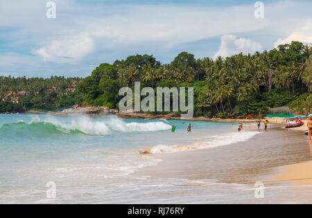 Les vagues sur le rivage de la plage de sable fin bordée de palmiers tropicaux à Surin Beach, sur la côte ouest de Phuket, Thaïlande Banque D'Images