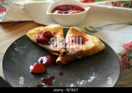 Crêpes maison avec du fromage cottage et les fraises dans une assiette. Fond de bois. Banque D'Images