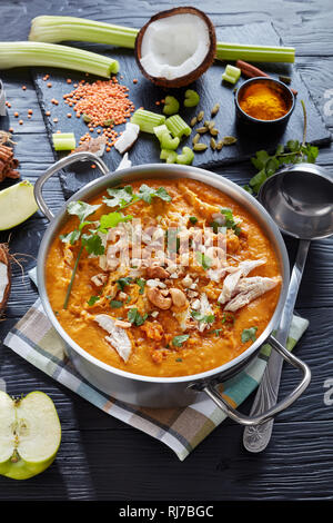 Soupe Mulligatawny épicé copieux avec de la viande de poulet frit arrosé avec dans un chaudron de cajou sur une table en bois noir, indien et une cuisine anglaise traditionnelle, vert Banque D'Images