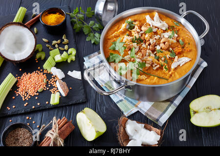 Soupe Mulligatawny épicé copieux avec de la viande de poulet frit arrosé avec dans un chaudron de cajou sur une table en bois noir avec des ingrédients, Affaires indiennes et l'engl Banque D'Images