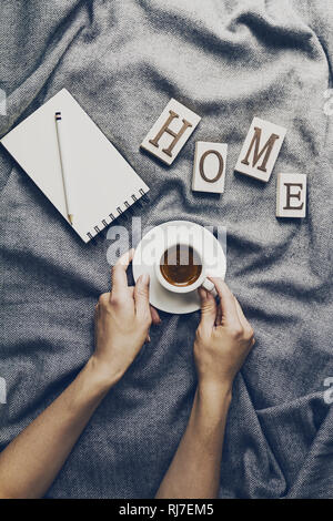 Femme hands holding café savoureux espresso dans petite tasse sur gris à carreaux. Home concept. Vue d'en haut. Banque D'Images