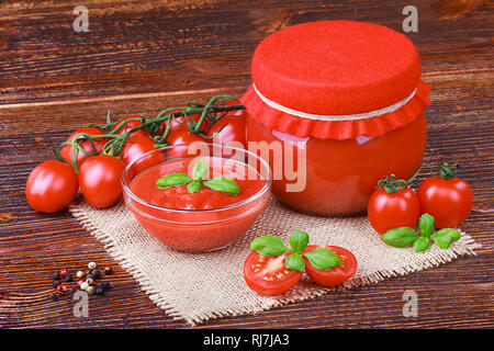 Pâte de tomates et les tomates mûres sur une vieille table en bois brun(selective focus). Banque D'Images