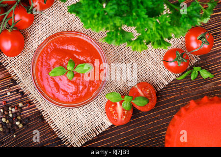 Pâte de tomates et les tomates mûres sur une vieille table en bois brun(selective focus). Banque D'Images