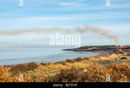 Gullane beach, East Lothian, Ecosse, Royaume-Uni, 5 février 2019. Météo France : tôt le matin est froid et forsty mais lumineux et ensoleillé le long de la côte du Firth of Forth. Pas du tout avec la brise, l'eau est très calme et une banque de brouillard se trouve au milieu de l'estuaire. Les gens à pied leurs chiens sur la plage à marée basse. Un panache de fumée s'élève de sous-bois en feu Banque D'Images