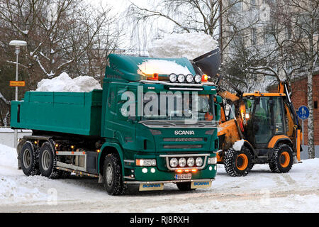 Salo, Finlande - le 2 février 2019 : la neige sur les charges du chargeur JCB green Scania P420 dump truck trailer pour être transportés à une zone de déversement de la neige. Banque D'Images