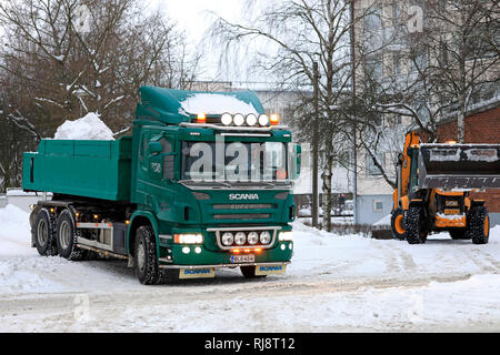 Salo, Finlande - le 2 février 2019 : la neige sur les charges du chargeur JCB green Scania P420 dump truck trailer pour être transportés à une zone de déversement de la neige. Banque D'Images