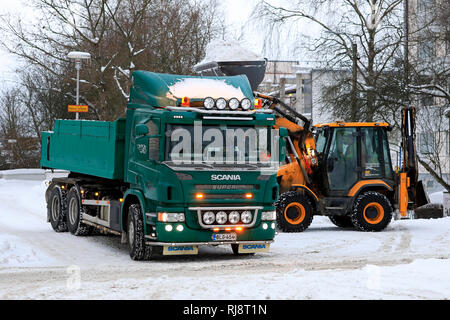 Salo, Finlande - le 2 février 2019 : la neige sur les charges du chargeur JCB green Scania P420 dump truck trailer pour être transportés à une zone de déversement de la neige. Banque D'Images