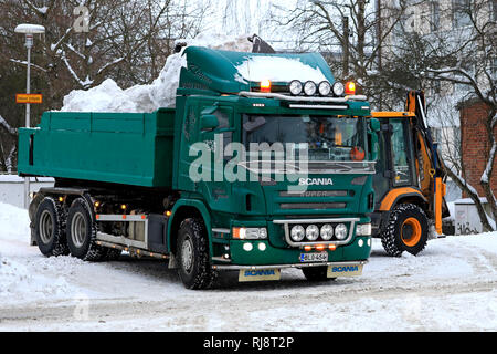 Salo, Finlande - le 2 février 2019 : la neige sur les charges du chargeur JCB green Scania P420 dump truck trailer pour être transportés à une zone de déversement de la neige. Banque D'Images