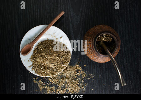 Photographie artistique de la yerba mate infusion, typique de l'Argentine, dans une assiette blanche, sur un fond de bois foncé Banque D'Images