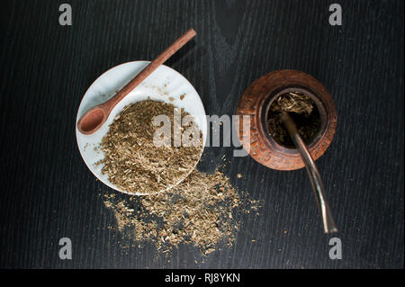 Photographie artistique de la yerba mate infusion, typique de l'Argentine, dans une assiette blanche, sur un fond de bois foncé Banque D'Images