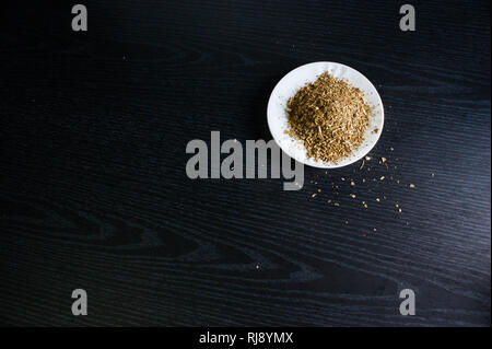 Photographie artistique de la yerba mate infusion, typique de l'Argentine, dans une assiette blanche, sur un fond de bois foncé Banque D'Images