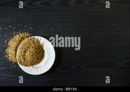 Photographie artistique de la yerba mate infusion, typique de l'Argentine, dans une assiette blanche, sur un fond de bois foncé Banque D'Images