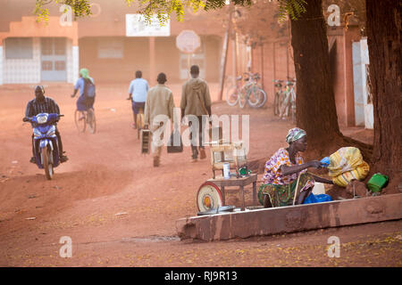 Yako, Burkina Faso, le 29 novembre 2016 ; la vie de la rue à l'extérieur de la SEMUS composé comme une femme se prépare à faire de petites boulettes d'aliments de rue s tôt le matin. Banque D'Images