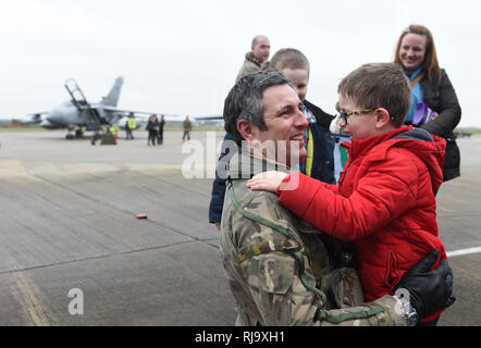 Commandant Commandant de l'Escadre Escadron IX James Heeps épouse son fils Henry, 6, après le dernier pilote RAF Tornado Gr4 retour à leur base à RAF Marham à Norfolk, après avoir réalisé les opérations dans le Moyen-Orient pour la dernière fois avant le départ de l'avion. Banque D'Images