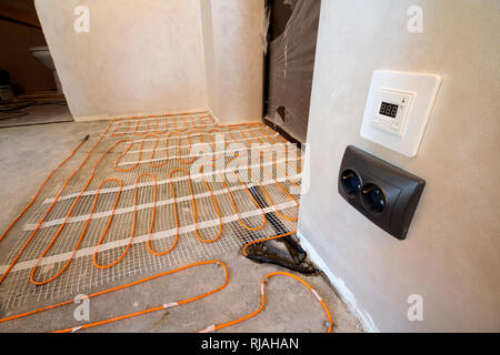 Chauffage électrique fil rouge du système installé sur le sol en ciment dans les petites nouvelles unfinished room avec plâtre des murs. La rénovation et la construction, mod Banque D'Images