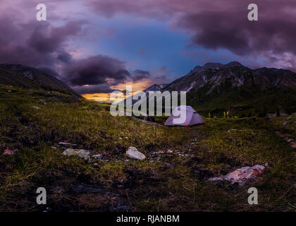 Panorama tente dans la montagne sur un fond de nuages pourpres au coucher du soleil Banque D'Images