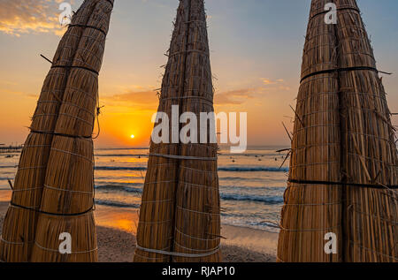 Roseau totora traditionnels bateaux le long de la plage de Huanchaco au coucher du soleil près de Trujillo, Pérou. Banque D'Images