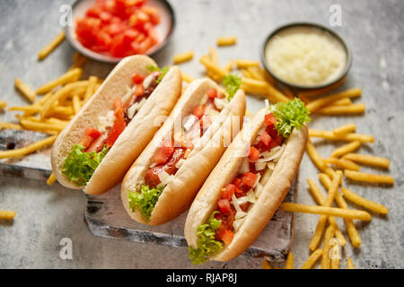 Assortiment de trois tasety hot dogs, placés sur une planche à découper en bois Banque D'Images