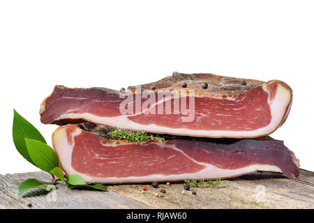 Bacon tyrolien typique sud divisé en deux halfes allongé sur une table rustique devant un fond blanc Banque D'Images