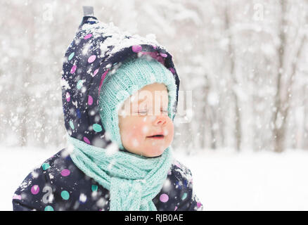 Bébé dans un pyjama d'hiver se réjouit dans la première neige Banque D'Images