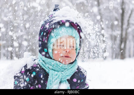 Bébé dans un pyjama d'hiver se réjouit dans la première neige Banque D'Images