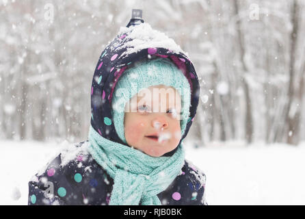 Bébé dans un pyjama d'hiver se réjouit dans la première neige Banque D'Images