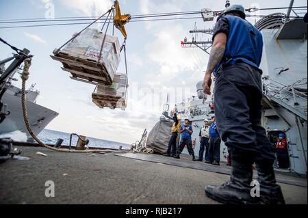 Eaux à l'EST DU JAPON (nov. 5, 2016) marins affectés à l'avant-déployés de la classe Arleigh Burke destroyer lance-missiles USS Barry (DDG 52) recevoir des palettes de nourriture à la mi-station de ravitaillement de navires au cours d'un ravitaillement en mer avec la commande de transport maritime militaire (MSC) de marchandises et de munitions Ship USNS Charles Drew (T-AKE 10) comme une partie de l'épée 17 Keen (KS17). KS17 est une bi, chef de l'état-major interarmées-dirigé, AMÉRICAINES DU PACIFIQUE-parrainé Terrain (FTX). KS17 est conçu pour répondre aux objectifs de défense mutuelle en augmentant la préparation au combat et l'interopérabilité Banque D'Images