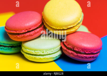 Gâteaux macarons colorés sur un fond bleu, rose, jaune vert gros plan dessert français pour le petit déjeuner Banque D'Images