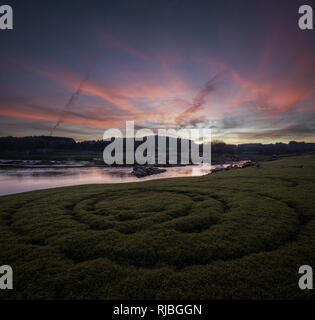 Coucher du soleil doré sur une rivière, avec une spirale dans l'herbe au premier plan, en O Paramo, Galice Banque D'Images