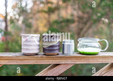 Théière en verre sur la balustrade de bois à l'extérieur sur le jardin de clôture avec deux tasses et japonais de thé matcha vert vibrant couleur dans matin libre Banque D'Images