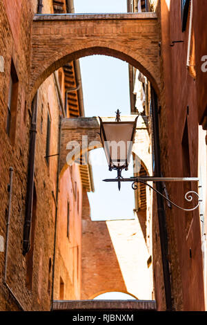 Sienne, Italie ruelle étroite dans la rue vieille ville médiévale historique village de Toscane avec personne et passage de roue jusqu'à la lanterne avec pendant la journée Banque D'Images