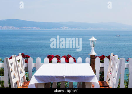 Dîner romantique nappe blanche chaises blanches sur le fond de la mer . Banque D'Images