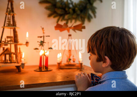 Garçon debout devant un buffet à la recherche de décorations de Noël Banque D'Images