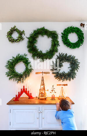Garçon debout devant un buffet à la recherche de décorations de Noël Banque D'Images