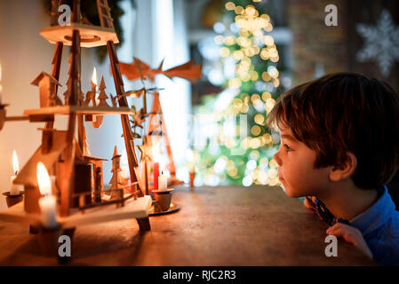 Garçon debout devant un buffet à la recherche de décorations de Noël Banque D'Images