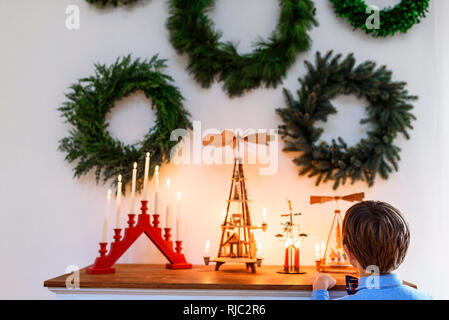 Garçon debout devant un buffet à la recherche de décorations de Noël Banque D'Images