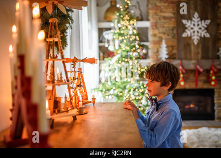 Garçon debout devant un buffet à la recherche de décorations de Noël Banque D'Images