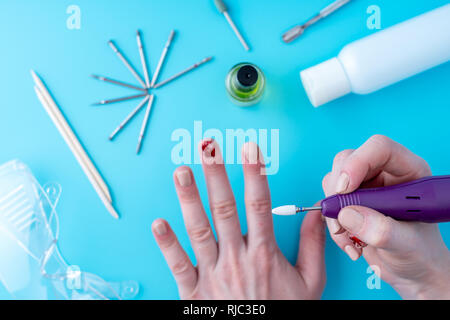 Femme faisant une manucure manucure professionnelle à l'aide de matériel de fraise sur le fond de l'outils. Vue de dessus de bleu Banque D'Images