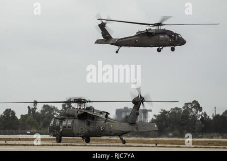 Une paire de Californie Army National Guard hélicoptères Black Hawk UH-60 décoller de Los Alamitos Army Airfield, Los Alamitos, Californie, 9 janvier 2018. Les hélicoptères, avec leur équipage et l'équipement de sauvetage, ont été activés à partir de l'aérodrome de vol à aider le pouvoir civil en réponse à storm-driven coulées dans les zones brûlées par les récents incendies en Californie du Sud. Huit hélicoptères de la Garde nationale de Californie ont été activés dans tout l'état. Banque D'Images